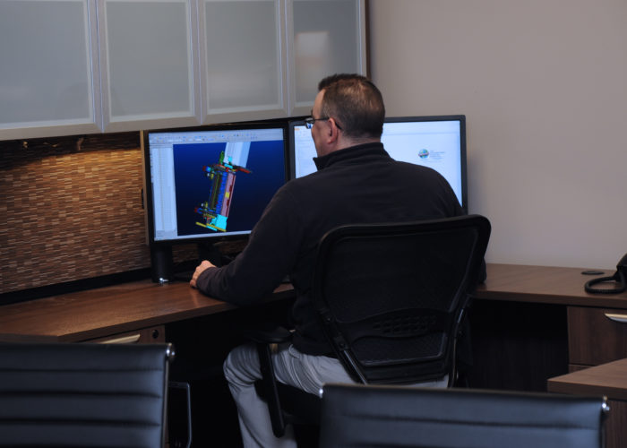 A man sitting at a desk with two computers.