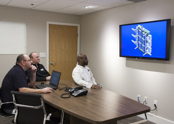 A group of people sitting around a table in front of a flat screen tv.