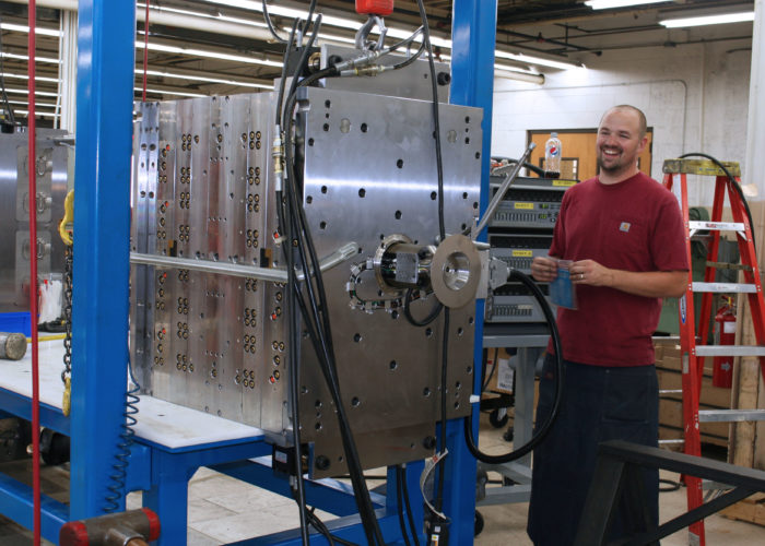 A man standing next to a machine in a factory.