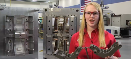 A woman holding up two wrenches in front of an assembly machine.